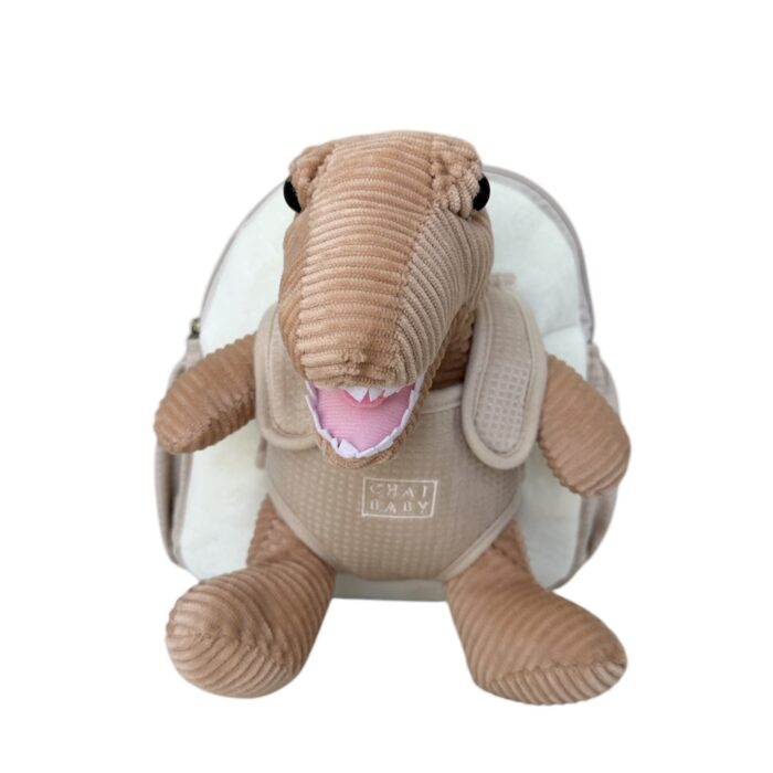 child with beige backpack on with harness and plush