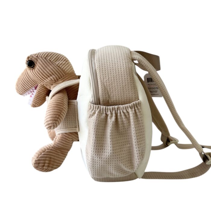 child with beige backpack on with harness and plush